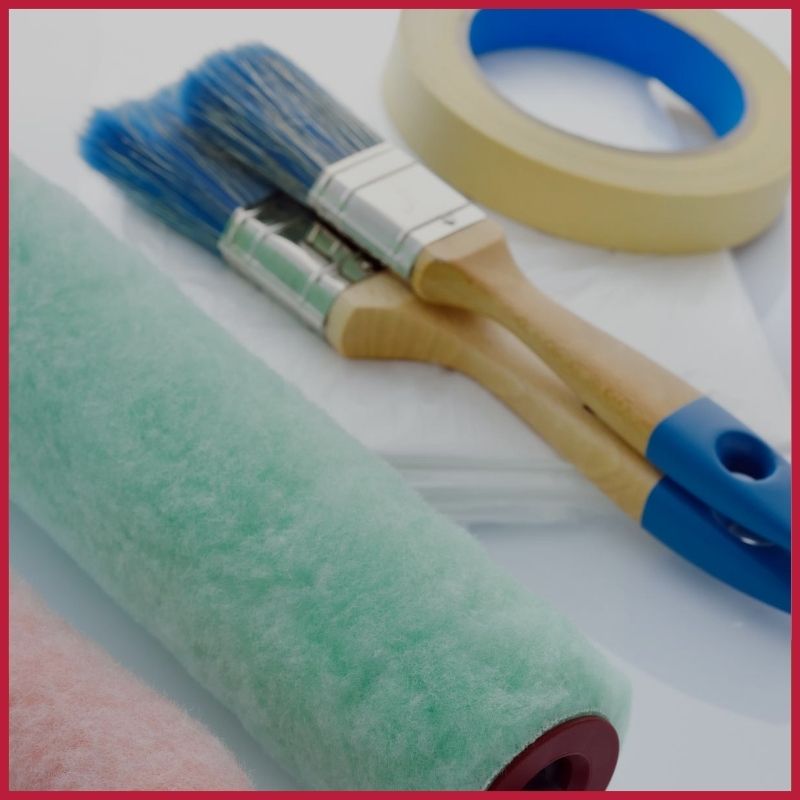 paint rollers, brushes and masking tape layed out in preparation of a painting project