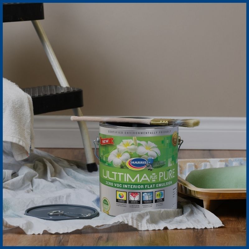 gallon of Harris Paint's Ultima Plus on the floor of a home, next to a step ladder, paint tray, paint roller and drop cloths